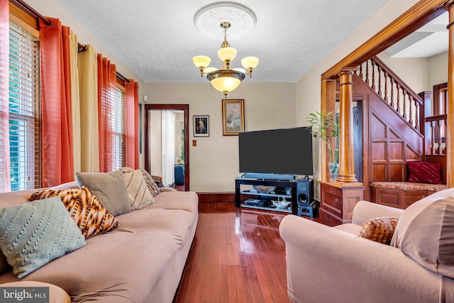 living room with a chandelier, wood-type flooring, stairs, baseboards, and a textured ceiling