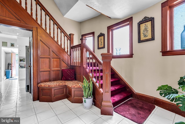stairway featuring plenty of natural light, tile patterned flooring, and baseboards
