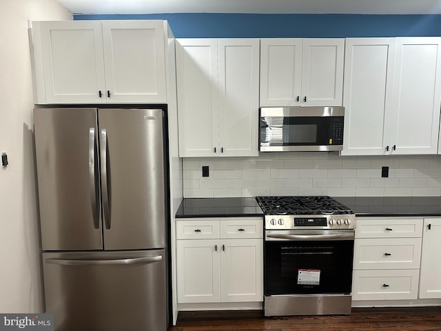 3406 Richmond St, Philadelphia, PA 19134 - kitchen featuring appliances with stainless steel finishes, dark countertops, white cabinets, dark wood-style flooring, and backsplash