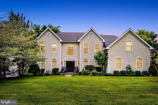 georgian-style home with a front lawn and roof with shingles