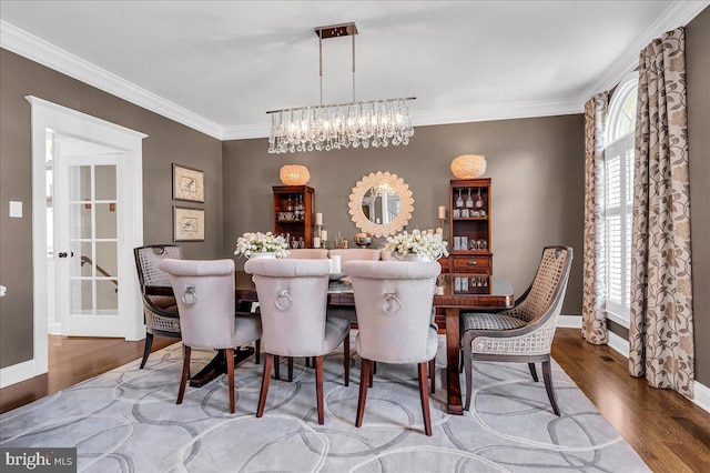 dining space featuring a chandelier, wood finished floors, crown molding, and baseboards