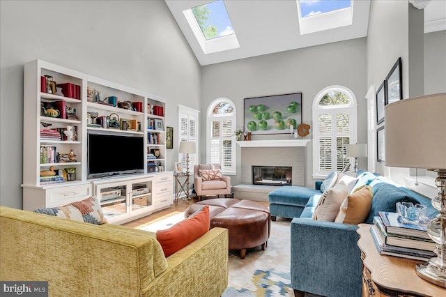 living area featuring high vaulted ceiling, a skylight, and a brick fireplace