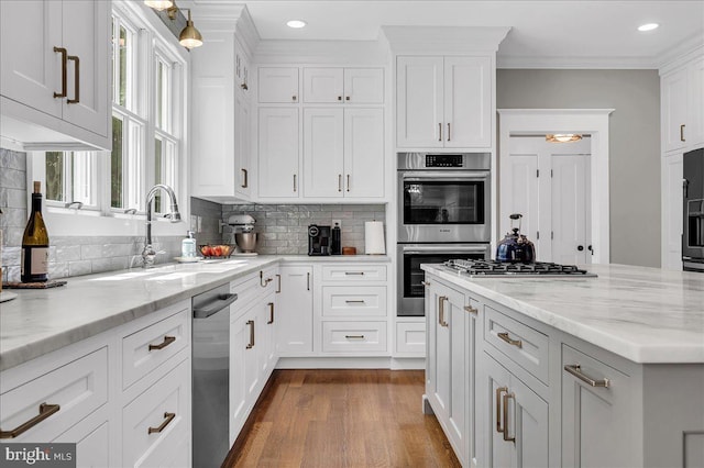 kitchen featuring a sink, appliances with stainless steel finishes, dark wood-type flooring, white cabinets, and tasteful backsplash