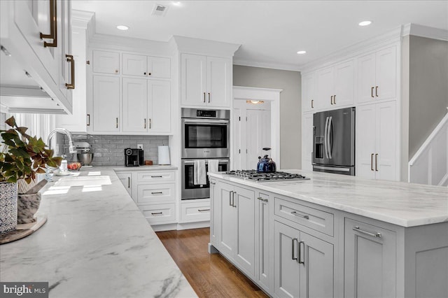 kitchen with stainless steel appliances, white cabinets, tasteful backsplash, light stone countertops, and recessed lighting