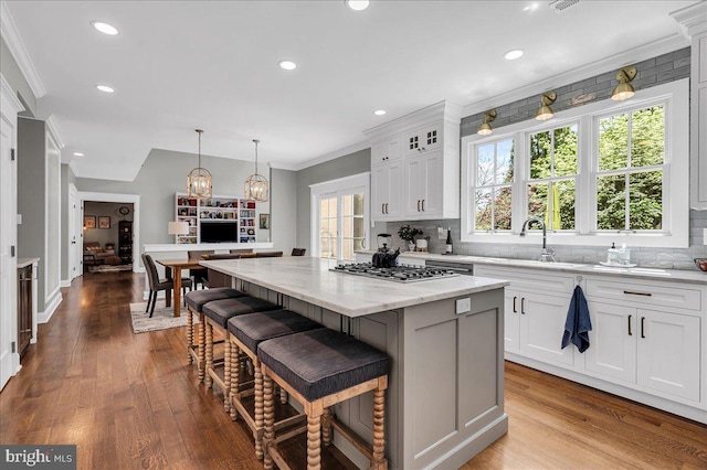kitchen with a sink, tasteful backsplash, a kitchen island, a kitchen bar, and recessed lighting