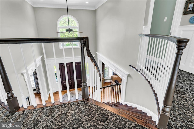 foyer featuring ceiling fan, a towering ceiling, stairway, a decorative wall, and ornamental molding
