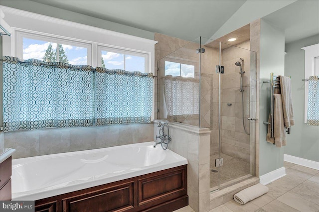 full bathroom with healthy amount of natural light, a garden tub, a shower stall, baseboards, and lofted ceiling