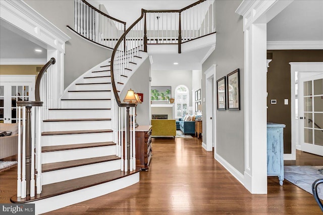 foyer with a fireplace, wood finished floors, stairs, crown molding, and baseboards