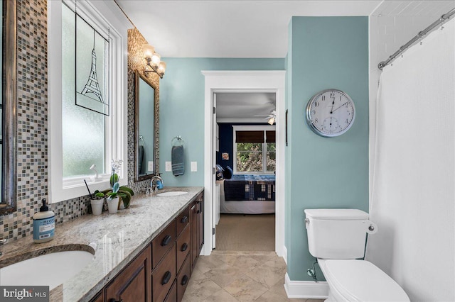 bathroom featuring toilet, decorative backsplash, double vanity, connected bathroom, and baseboards