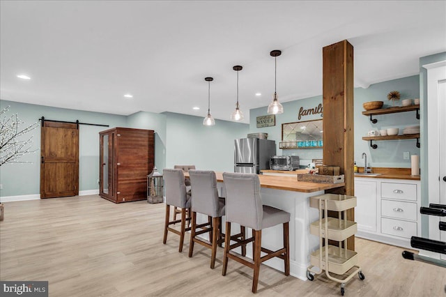 kitchen with wood counters, freestanding refrigerator, white cabinets, open shelves, and a sink