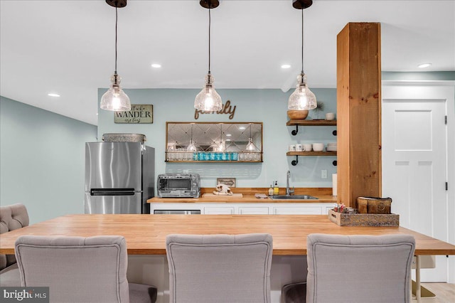 indoor wet bar featuring freestanding refrigerator, pendant lighting, and recessed lighting