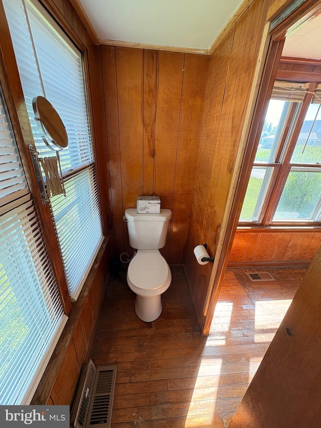 bathroom with hardwood / wood-style floors, wood walls, and toilet