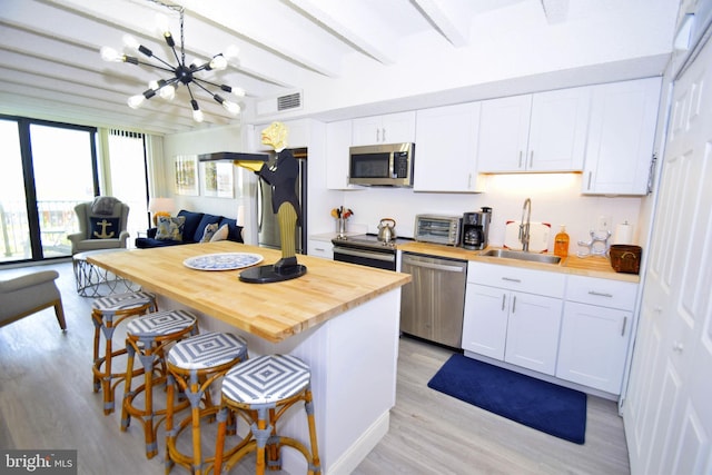 7604 Coastal Hwy Unit 2B, Ocean City, MD 21842 - kitchen featuring stainless steel appliances, a sink, a chandelier, wood counters, and light wood-style flooring