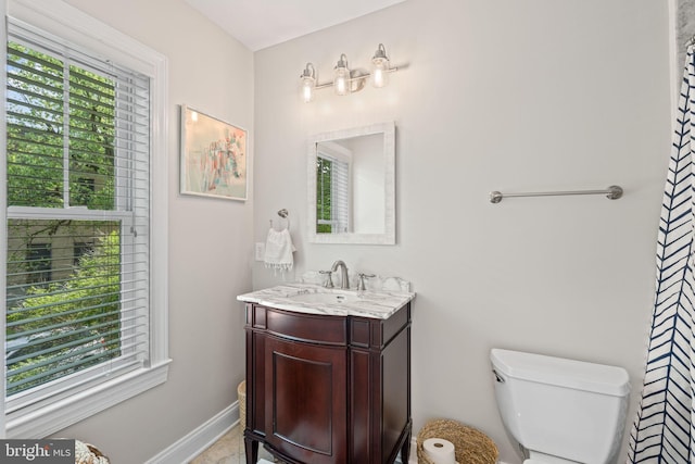 full bathroom with toilet, vanity, and baseboards