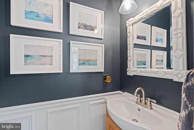 bathroom with a decorative wall, wainscoting, and vanity