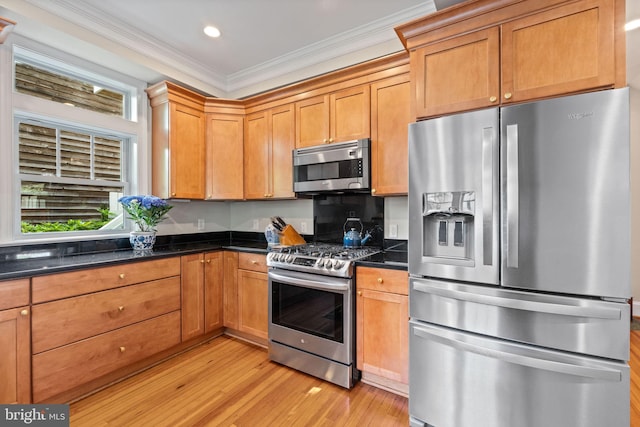 kitchen featuring appliances with stainless steel finishes, ornamental molding, light wood-style flooring, recessed lighting, and dark stone countertops