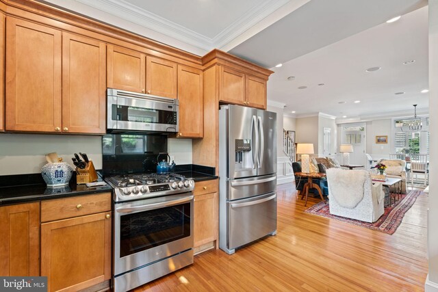 kitchen featuring stainless steel appliances, ornamental molding, dark countertops, light wood finished floors, and open floor plan