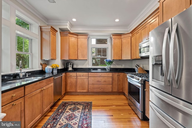kitchen featuring stainless steel appliances, a sink, light wood-style floors, crown molding, and recessed lighting
