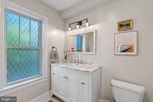 half bath featuring toilet, vanity, and baseboards