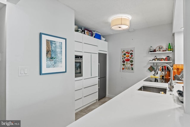 2141 Wisconsin Ave NW Unit 103, Washington, DC 20007 - kitchen featuring appliances with stainless steel finishes, light countertops, white cabinets, open shelves, and a sink