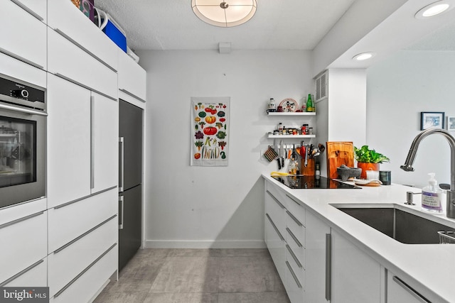 2141 Wisconsin Ave NW Unit 103, Washington, DC 20007 - kitchen with a sink, black electric cooktop, stainless steel oven, white cabinets, and light countertops