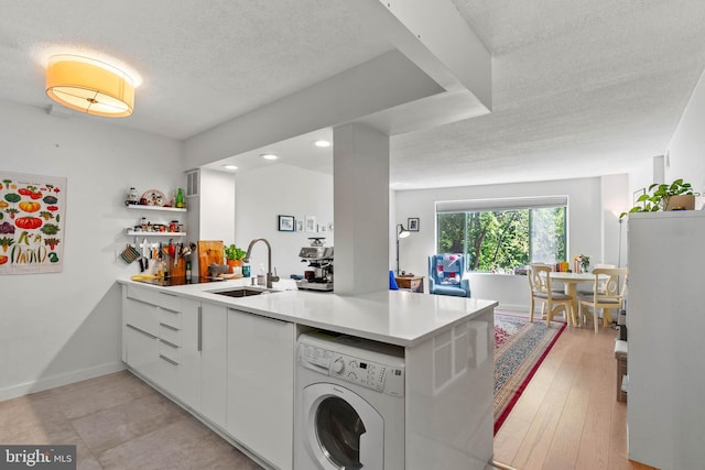 2141 Wisconsin Ave NW Unit 103, Washington, DC 20007 - kitchen with washer / clothes dryer, a sink, a textured ceiling, white cabinetry, and light countertops