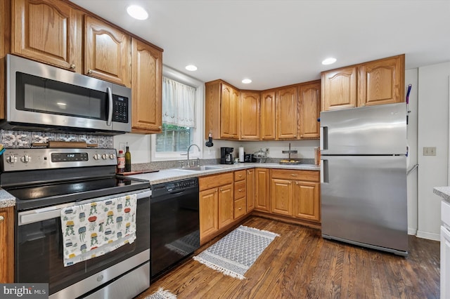 kitchen with appliances with stainless steel finishes, a sink, dark wood finished floors, light countertops, and recessed lighting