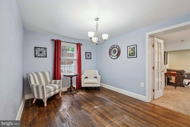 sitting room with a chandelier, baseboards, and wood finished floors
