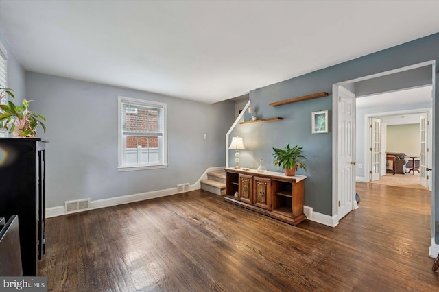 unfurnished living room with wood finished floors, stairway, and baseboards