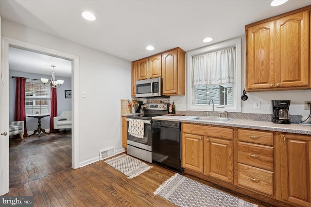 kitchen featuring appliances with stainless steel finishes, a sink, dark wood finished floors, recessed lighting, and light countertops