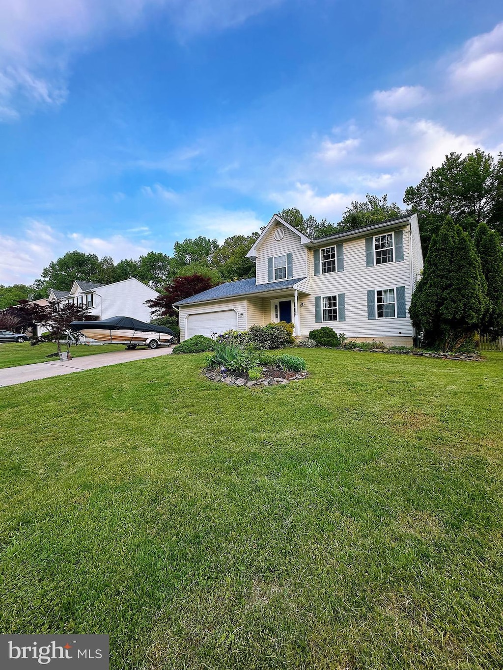 view of front of home featuring an attached garage, concrete driveway, and a front yard