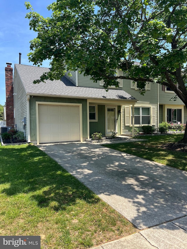 view of front of home with a garage, driveway, a front yard, roof with shingles, and board and batten siding