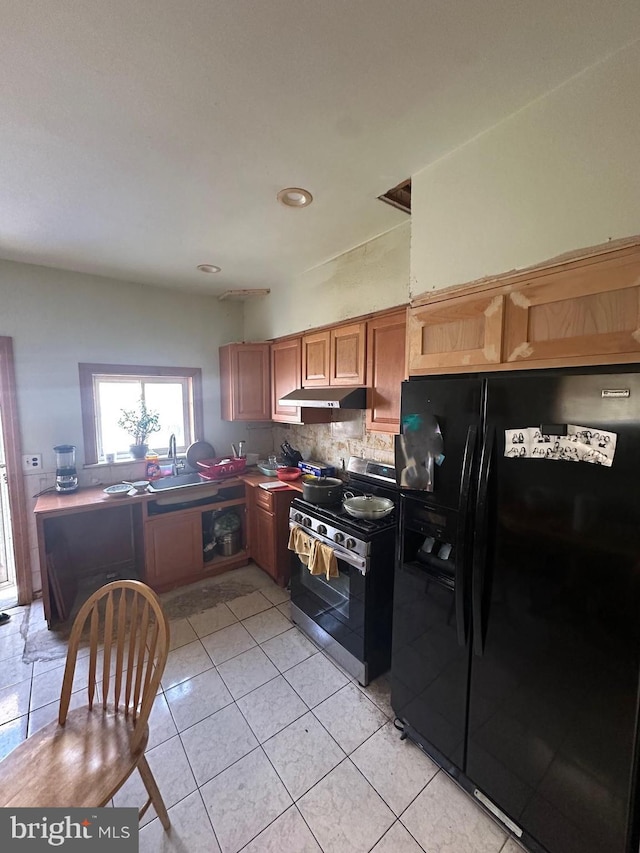 1139 Snyder Ave, Philadelphia, PA 19148 - kitchen featuring black fridge with ice dispenser, stainless steel gas range, under cabinet range hood, backsplash, and light tile patterned floors