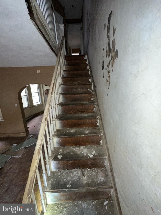 staircase featuring arched walkways