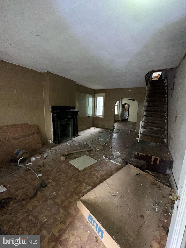 unfurnished living room with arched walkways, a fireplace, and stairway
