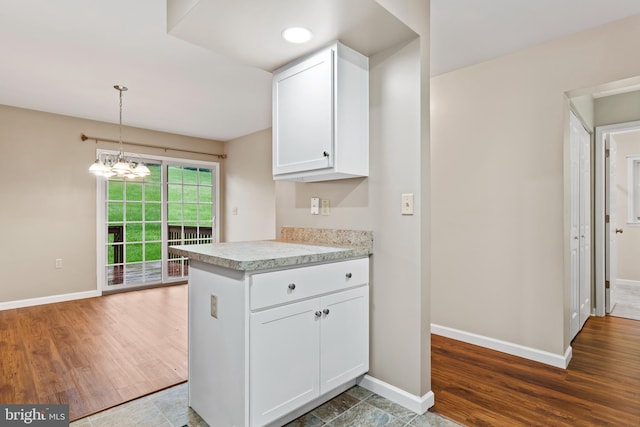 kitchen featuring light countertops, baseboards, white cabinets, and wood finished floors