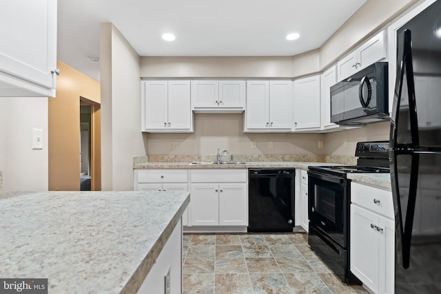 kitchen featuring black appliances, a sink, white cabinetry, and stone finish flooring
