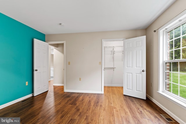 unfurnished bedroom with wood finished floors, baseboards, and a closet
