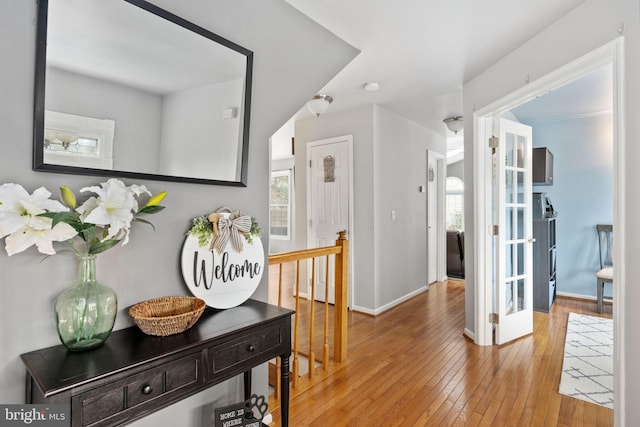 hall featuring hardwood / wood-style floors, plenty of natural light, baseboards, and an upstairs landing