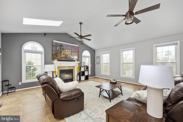living room with healthy amount of natural light, ceiling fan, lofted ceiling, and a skylight