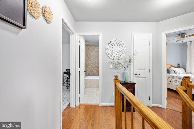 hall with light wood-style floors and baseboards