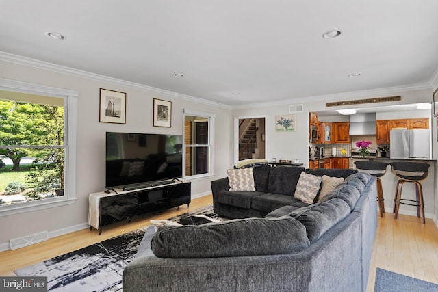 living room with crown molding, light wood-type flooring, stairway, and baseboards