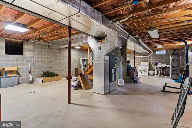 unfinished below grade area with heating unit, concrete block wall, and stairs