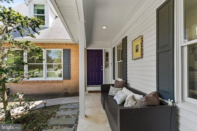 entrance to property featuring covered porch and brick siding