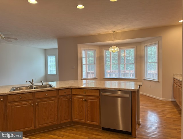 kitchen featuring dishwasher, a sink, brown cabinets, wood finished floors, and recessed lighting