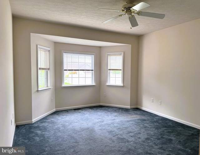 unfurnished room featuring dark colored carpet, ceiling fan, baseboards, and a textured ceiling