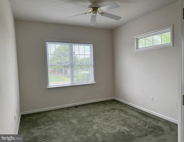 unfurnished room featuring dark carpet, a ceiling fan, and baseboards
