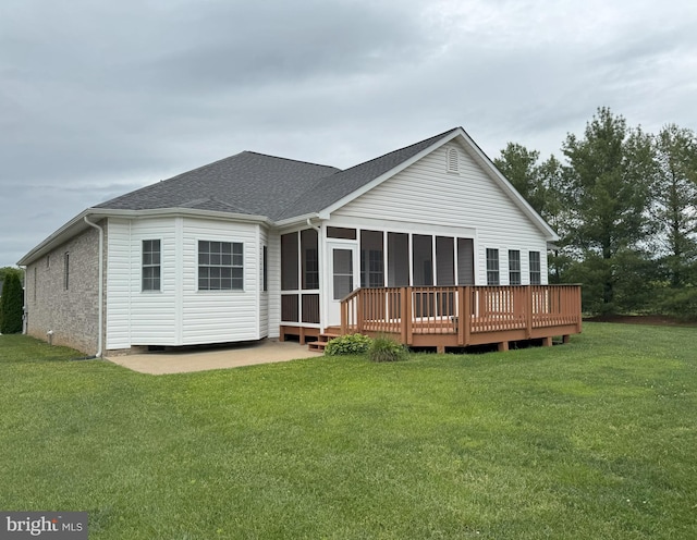 rear view of property with a shingled roof, a sunroom, a lawn, and a wooden deck