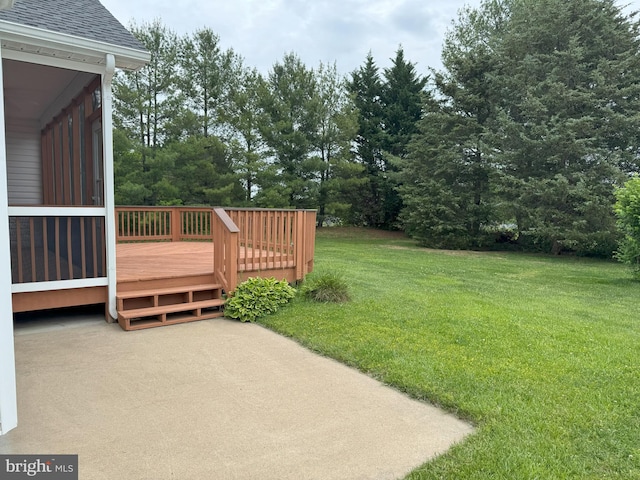 view of grassy yard with a wooden deck and view of scattered trees