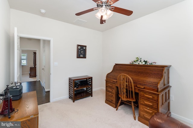 carpeted office space featuring ceiling fan and baseboards